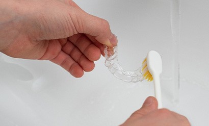 Patient cleaning clear aligner in sink