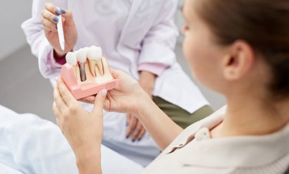 a patient holding a model of dental implants 