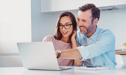 a couple looking at a laptop and smiling