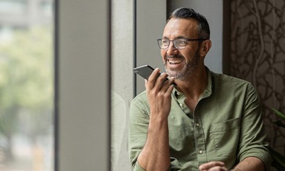 Man with glasses smiling while talking on phone