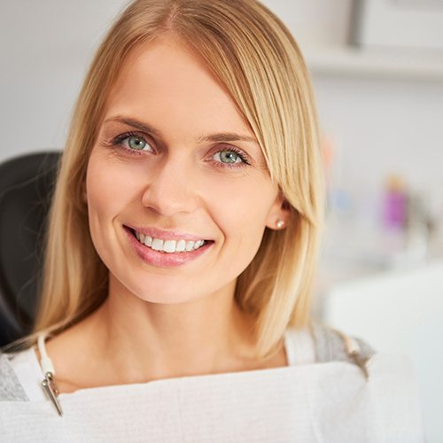 Blonde woman sitting in dental chair and smiling