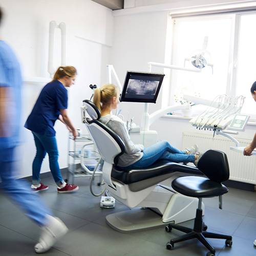 How We Handle Dental Emergencies: a person sitting in a dental chair with staff working around them