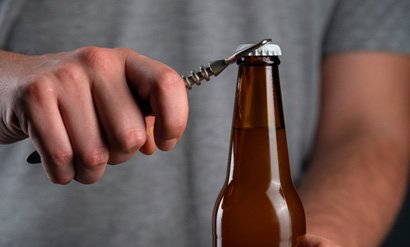 Closeup of man using bottle cap opener