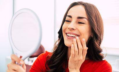 a patient smiling and looking in a mirror