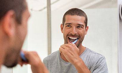  man smiling while brushing his teeth