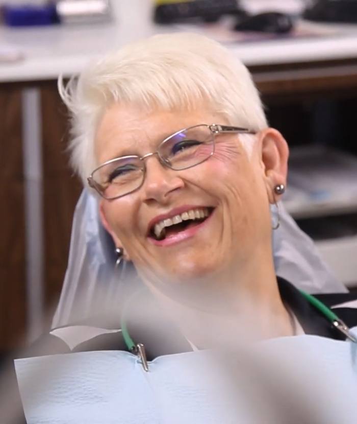 woman with glasses smiling at dentist