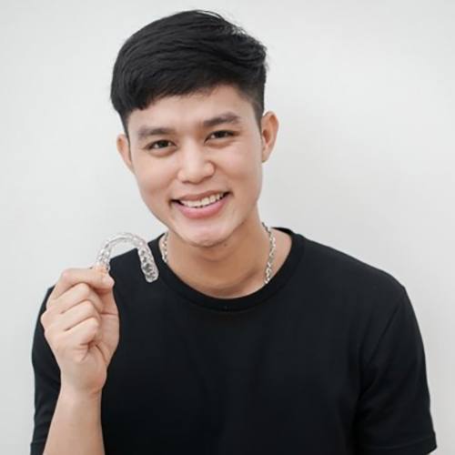 young man holding a clear Invisalign aligner