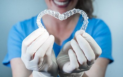 dental hygienist holding two clear aligners in the shape of a heart