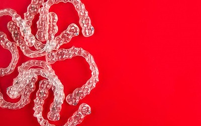several clear aligners against a red background