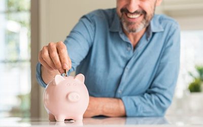 man putting coins into a pink piggy bank