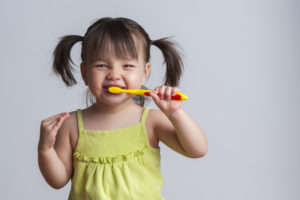 Smiling girl brushing her teeth