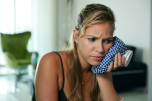 Woman with toothache holding heating pad to face