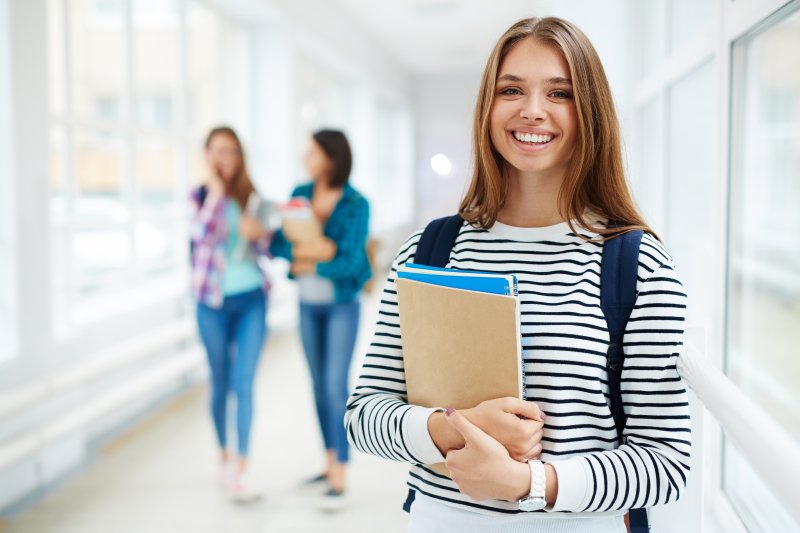 teenager holding books in school