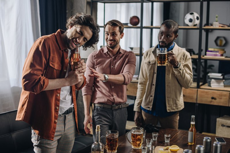 person opening a bottle with their teeth as friends watch