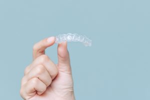 Person holding an Invisalign clear aligner